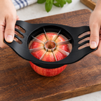 Cortador negro en uso sobre una manzana, con las manos apoyadas en ambas asas.