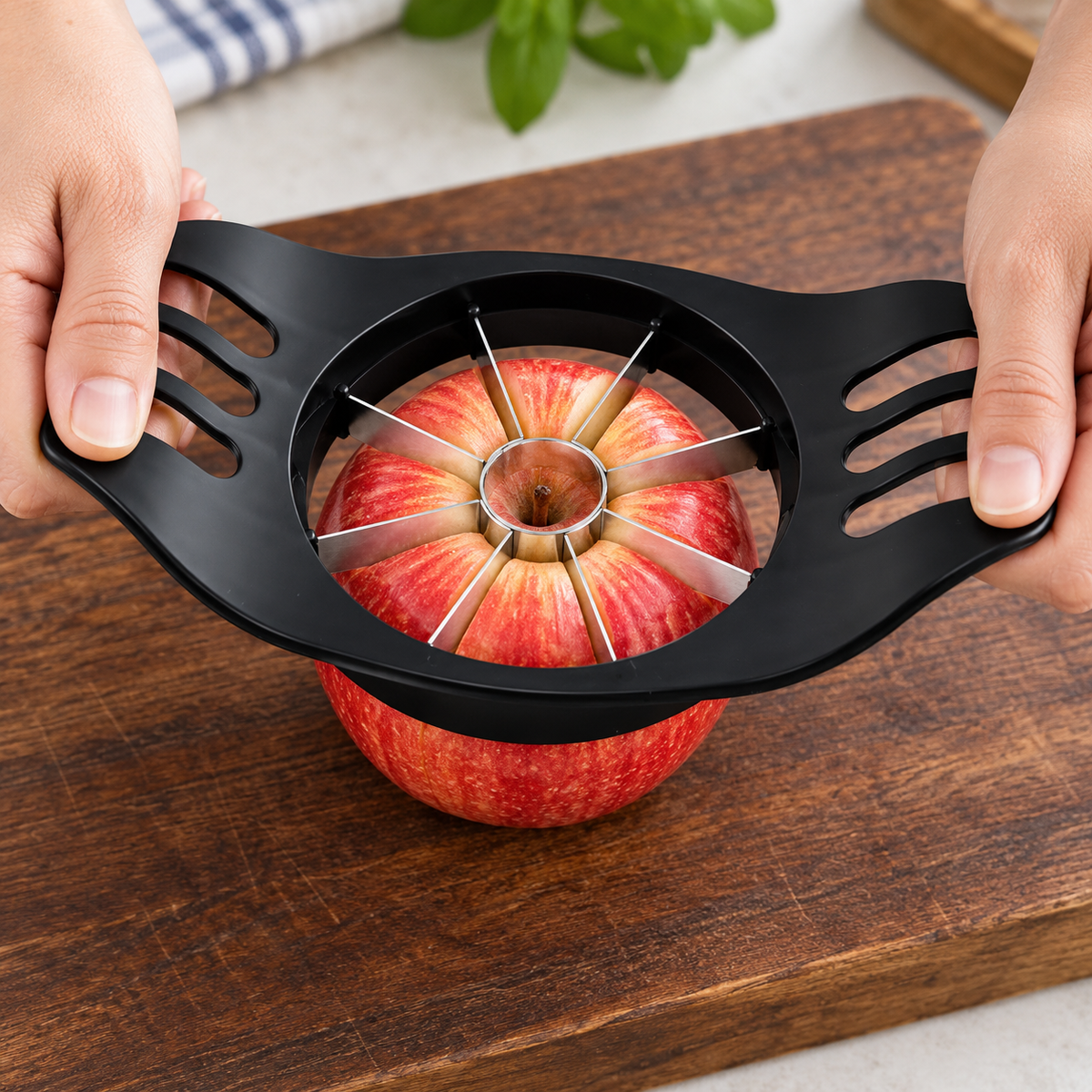 Cortador negro en uso sobre una manzana, con las manos apoyadas en ambas asas.