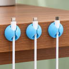 Detalle de tres organizadores sujetando cables en el borde de una mesa.