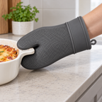Vista del producto: una manopla de silicón gris oscuro, dedos unidos en silueta redonda y pulgar separado; textura cuadriculada fina en palma, borde liso, puño rectangular ancho con dos bordes y pequeño aro lateral. Ambientación no incluida.
