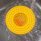 Detalle del colador amarillo colocado en el desagüe, con su rejilla y perforaciones visibles.