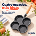 Portada Vendalia: sartén negro cuádruple con cuatro cavidades circulares en arreglo2x2, contorno de trébol, mango cilíndrico tipo madera naranja con ranuras finas, cuello negro, unión plateada y aro metálico para colgar. Alimentos y ambientación no incluidos.