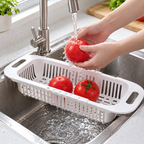 Cesta retráctil en uso al lavar verduras; alimentos y fregadero no incluidos.