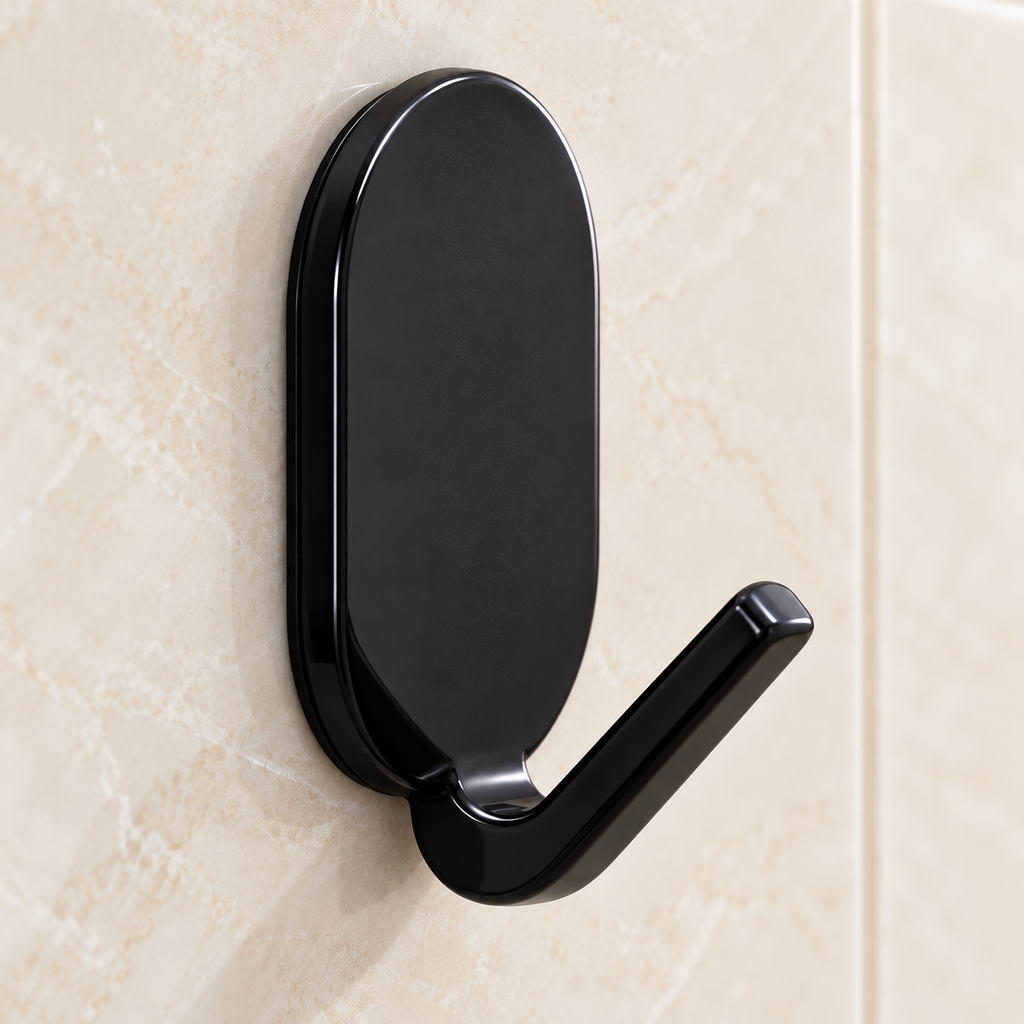 Gancho adhesivo negro con placa oval vertical y brazo corto inclinado — detalle del producto