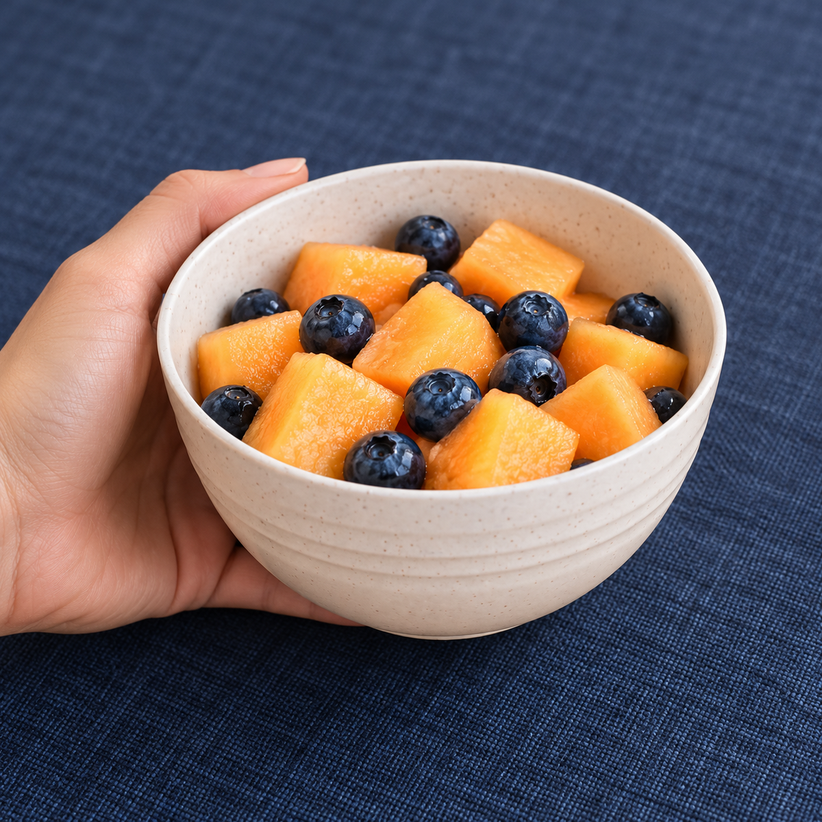 Bowl beige de 350 ml en uso para servir una porción de fruta; alimentos no incluidos.