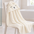 Toalla marfil con capucha de osito extendida en ambiente de baño