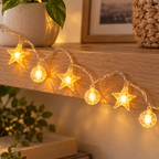 Luces Decorativas LED en Forma de Estrella en ambiente de hogar — Vendalia. Fotografía de detalle de un tramo de la serie; incluye 20 luces en 3 metros (10 estrellas y 10 bolitas). Los objetos decorativos del ambiente no están incluidos.
